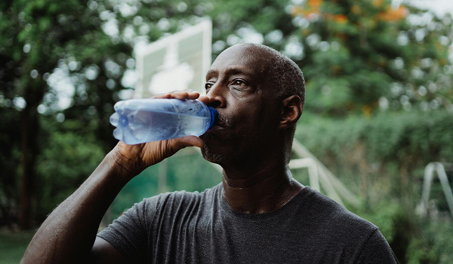 black man drinking water at basketball court