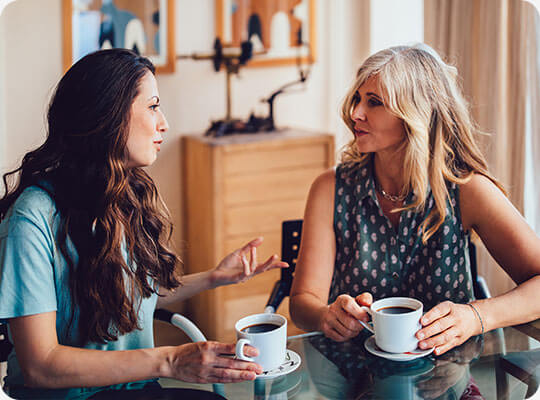 Two women share a story over coffee