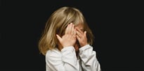 child with hands over eyes 